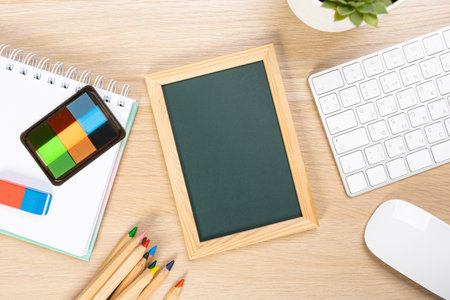 School chalkboard mockup on work desk. Composition of a student's desk with stationery items, toys, snack. Empty board for promo textの写真素材