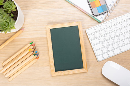 School chalkboard mockup on work desk. Composition of a student's desk with stationery items, toys, snack. Empty board for promo textの写真素材