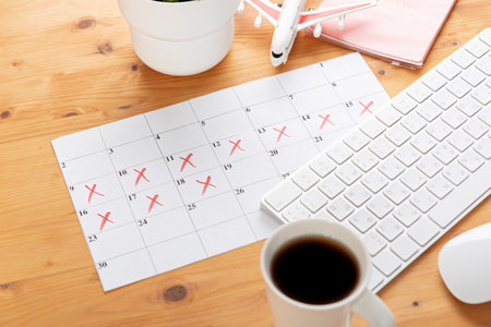 Calendar and reminders for business trip, travel and vacation. planner with airplane model on desktop with keyboard, mouse, coffee and succulent. marking important dates and days in a diary at the office desk. Reminder conceptの写真素材