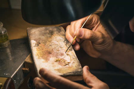 Hands of a craftsman jeweler working on jewelry. Goldsmith. Goldsmith workshop jewels and articles of work valueの写真素材