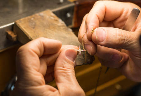 Hands of a craftsman jeweler working on jewelry. Goldsmith. Goldsmith workshop jewels and articles...