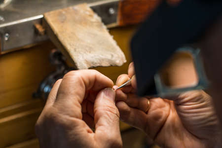 Hands of a craftsman jeweler working on jewelry. Goldsmith. Goldsmith workshop jewels and articles...