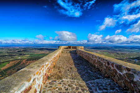 Landscape and castle of the city of Feria located in Extremadura, Spain. Landscape of a town and its castle with a beautiful valley and blue sky surrounded by nature.のeditorial素材
