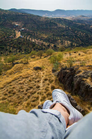 Point of view of a hiker in white sneakers overlooking a picturesque nature landscape. Relaxing hiker overlooking a pretty valley. Natureの写真素材