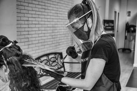 Hairdressers adapt to new security measures to prevent coronavirus. COVID 19. Hairdressers wear protective screens and sanitary masks. Badajoz, Spainのeditorial素材