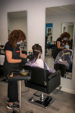 Hairdressers adapt to new security measures to prevent coronavirus. COVID 19. Hairdressers wear protective screens and sanitary masks. Badajoz, Spainのeditorial素材
