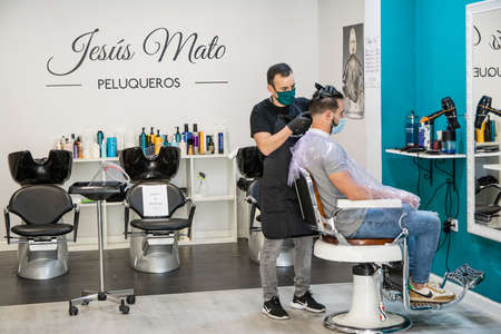 Hairdressers adapt to new security measures to prevent coronavirus. COVID 19. Hairdressers wear protective screens and sanitary masks. Badajoz, Spainのeditorial素材