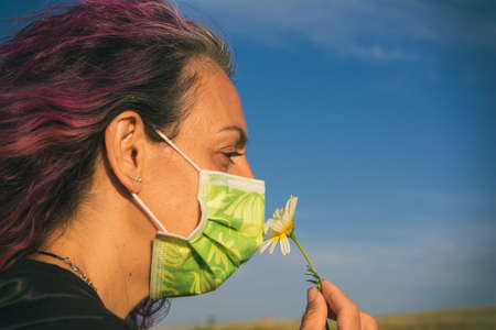 Woman With A Sanitary Mask After The  Outbreak In Spain. Adult Woman In The Field Enjoying Nature And Smelling A Flower.   Lifestyle.の写真素材
