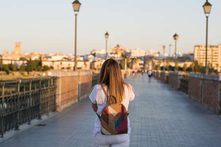 Rear View Of A Woman Walking Through The City Using Her Mobile Phone.