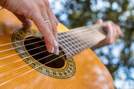 Playing The Spanish Guitar. Close-up Of A Woman's Hands Playing Guitar In A Natural Park.の写真素材