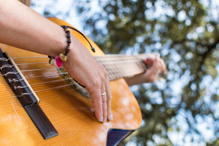Playing The Spanish Guitar. Close-up Of A Woman's Hands Playing Guitar In A Natural Park.の写真素材