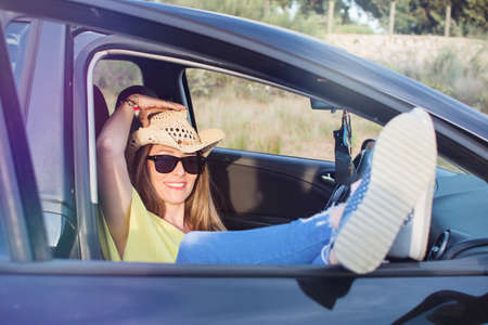 Beautiful Young Woman Resting Inside Her Car Enjoying The Sunset. She Wears A Cowboy Hat. Travel...