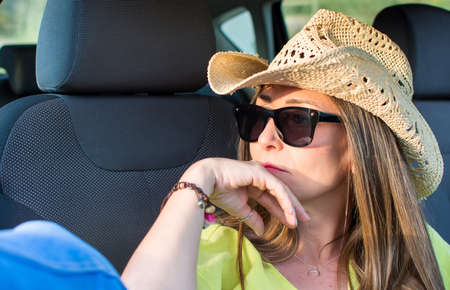Beautiful Young Woman Resting Inside Her Car Enjoying The Sunset. She Wears A Cowboy Hat. Travel...