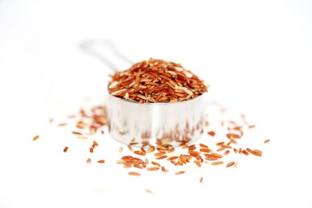 A horizontal color photograph of red cargo rice in a tin measuring cup.の写真素材