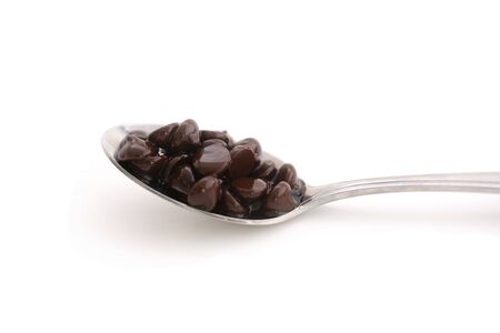 A horizontal color photograph of chocolate chips on a spoon against a white background.の写真素材