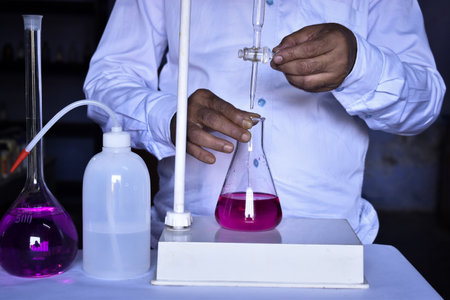 The scientist is conducting an acid-base titration in the lab, measuring precisely the amount of acid or base needed to neutralize a solution. Accurate results are critical in this essential chemical process.の写真素材