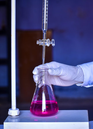 The student is doing acid-base titration, measuring and adding solutions with precision until neutralization. This experiment helps in learning chemistry.の写真素材