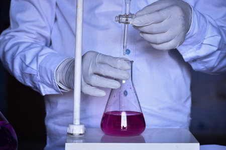 The scientist is conducting an acid-base titration in the lab, measuring precisely the amount of acid or base needed to neutralize a solution. Accurate results are critical in this essential chemical process.の写真素材