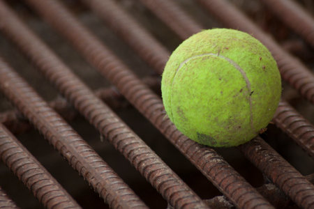 Yellow tennis ball on red iron barsの写真素材