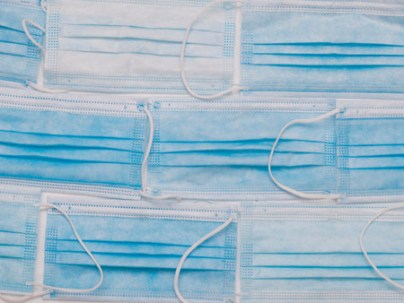 Blue surgical masks placed on a white cloth as if they formed a brick wallの写真素材