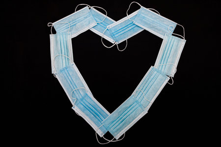 A heart made of blue surgical masks on a black cloth.の写真素材