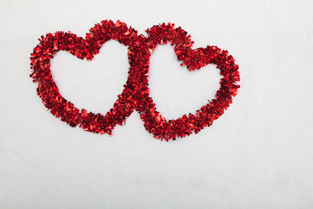 Two red decorative hearts located near the upper right corner of the image placed on a white fabric.の写真素材