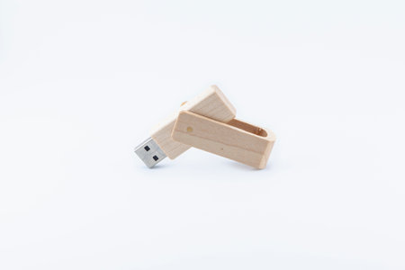 Wooden pen drive placed on a white background, open at an obtuse angle with the USB connector pointing down.の写真素材