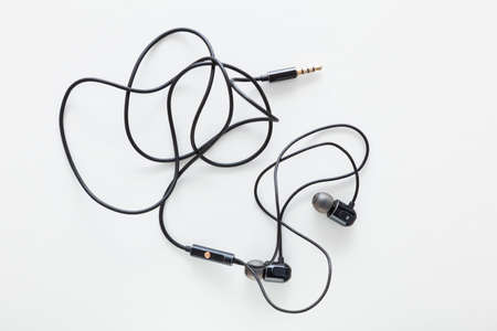 Wired silicone earphones with jack plug isolated on white background. In the middle of the cable...