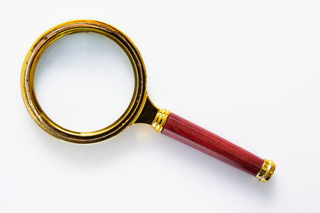 Golden magnifying glass with the plastic handle imitating wood isolated on a white background.の写真素材