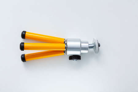 Small folded tripod with yellow legs lying on a white background. The base of the legs is made of black rubber.の写真素材