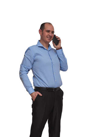 Bald guy dressed in blue shirt and black pants having a conversation via his smartphone isolated on white background. May be an office worker or banker.の写真素材