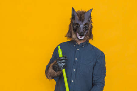 On a yellow background there is a werewolf dressed in a blue shirt is mopping the floor, you can see he is holding a mop stick or broom.の写真素材