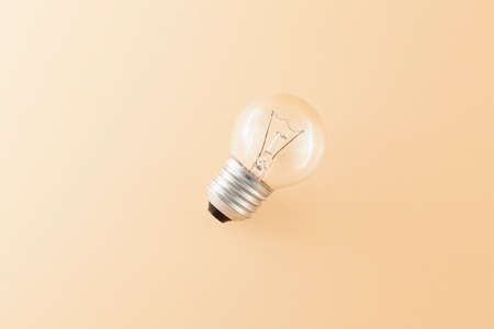Top view of a round tungsten filament bulb isolated on a beige background.の写真素材