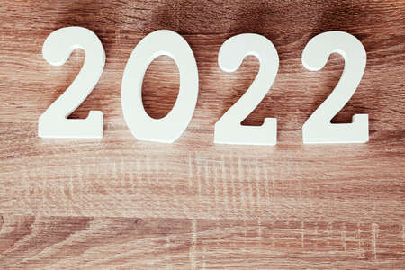 The number 2022 made of white wood on an oak wood board. Under the number there is copy space and at...