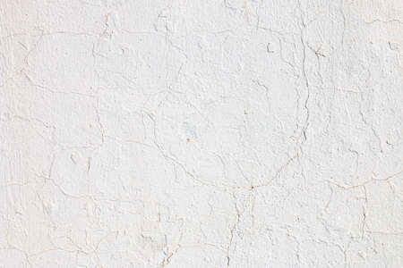 Wall plastered with cement and painted with white paint. The texture of cracks and imperfections can be seen.の写真素材