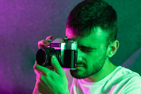 Portrait of a young bearded Caucasian man posed taking photos with an antique camera framed...