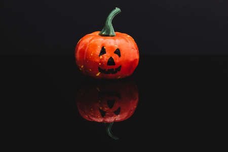 Halloween pumpkin with typical face isolated on black reflective surface. Background is dark.の写真素材