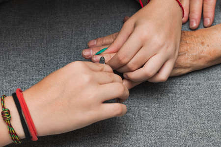 Close-up of the hands of two unrecognizable women, one young and one old, having a manicure. The...