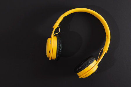 Yellow wireless headphones isolated on a dark background.
