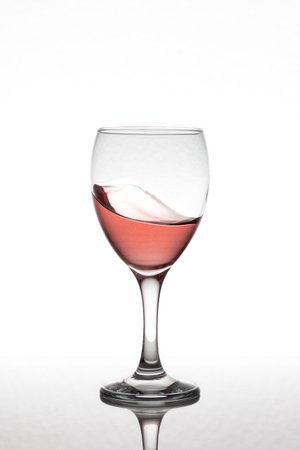 Motion glass of rose wine isolated on a white background over a reflective surface.の写真素材