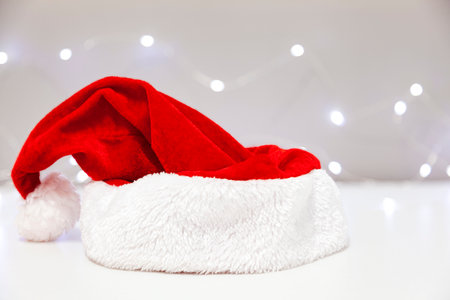 Isolated red Santa Claus hat over a white table. Some lights are blurred at background.の写真素材