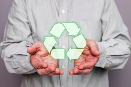 Close-up of an unrecognizable person's hands holding a floating recycling symbol.の写真素材