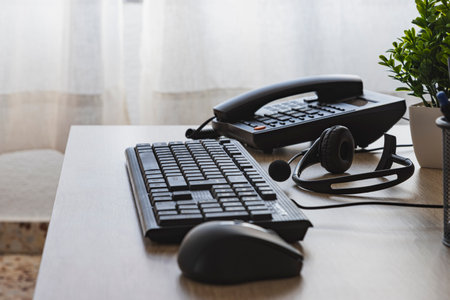 Office desk with telephone and computer keyboard and mouseの写真素材