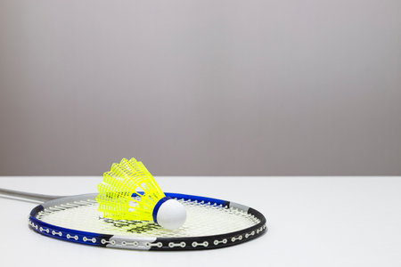 Close-up of a badminton racket with a yellow shuttlecock on its strings on a white surfaceの写真素材