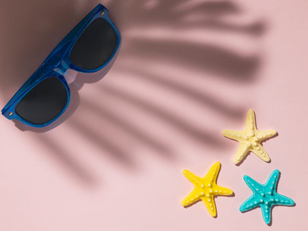 Sunglasses and starfish creating a summer holiday concept with palm shadowの写真素材