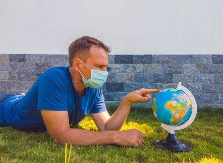 Man wearing Face Mask holding the Earth globe world map in hand. Quarantine yourself to protect spread virus. When can travel again. Epidemic pandemic coronavirus 2019-ncov sars covid-19 virus conceptの写真素材