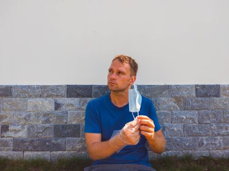 Portrait of guy with a medical mask. Outside walking in the garden near modern summer house. He wants to breathe, wait for the end of quarantine Covid19 isolation and beginning of normal life againの写真素材