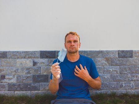 Portrait of guy with a medical mask. Outside walking in the garden near modern summer house. He...