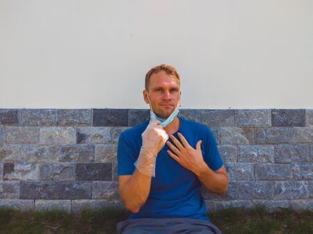 Portrait of guy with a medical mask. Outside walking in the garden near modern summer house. He wants to breathe, wait for the end of quarantine Covid19 isolation and beginning of normal life againの写真素材