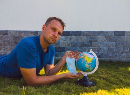Man wearing Face Mask holding the Earth globe world map in hand. Quarantine yourself to protect spread virus. When can travel again. Epidemic pandemic coronavirus 2019-ncov sars covid-19 virus conceptの写真素材